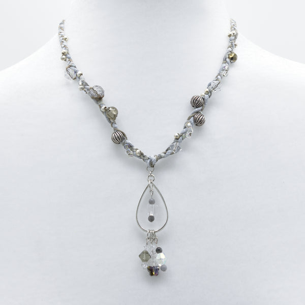 artisan crafted mid length necklace with hand sewn cords from cotton batik fabric braided with cotton cords embellished with crystals and beads and a a silver drop
